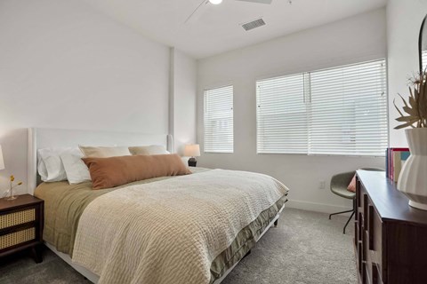 Apartments near Denver International Airport in Denver, CO, - Edera - Bright Bedroom With Soft Neutral Bedding, Large Windows With Blinds, Ceiling Fan, Carpeted Flooring, And Desk Seating