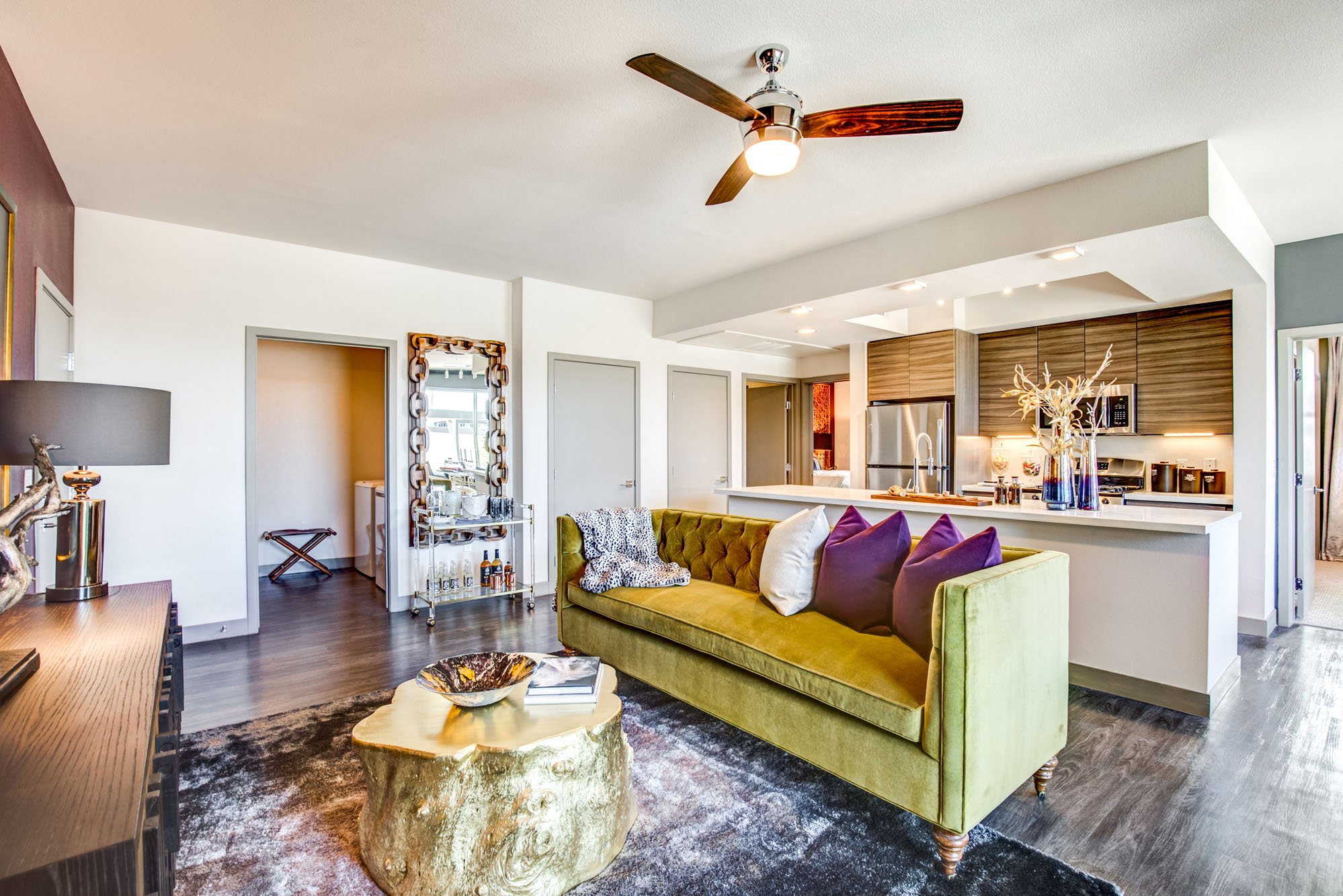 a living room with a green couch and a ceiling fan