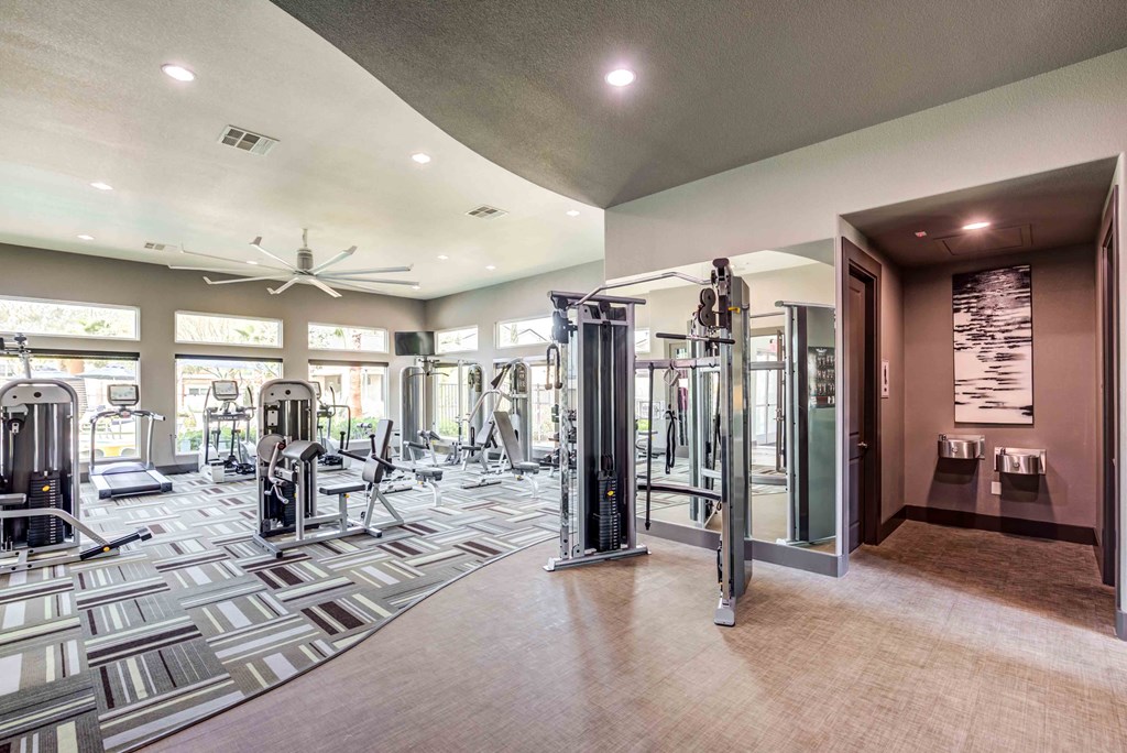 a gym with cardio machines and a ceiling fan