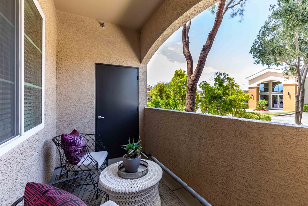 a balcony with a black door and a patio with chairs and a table