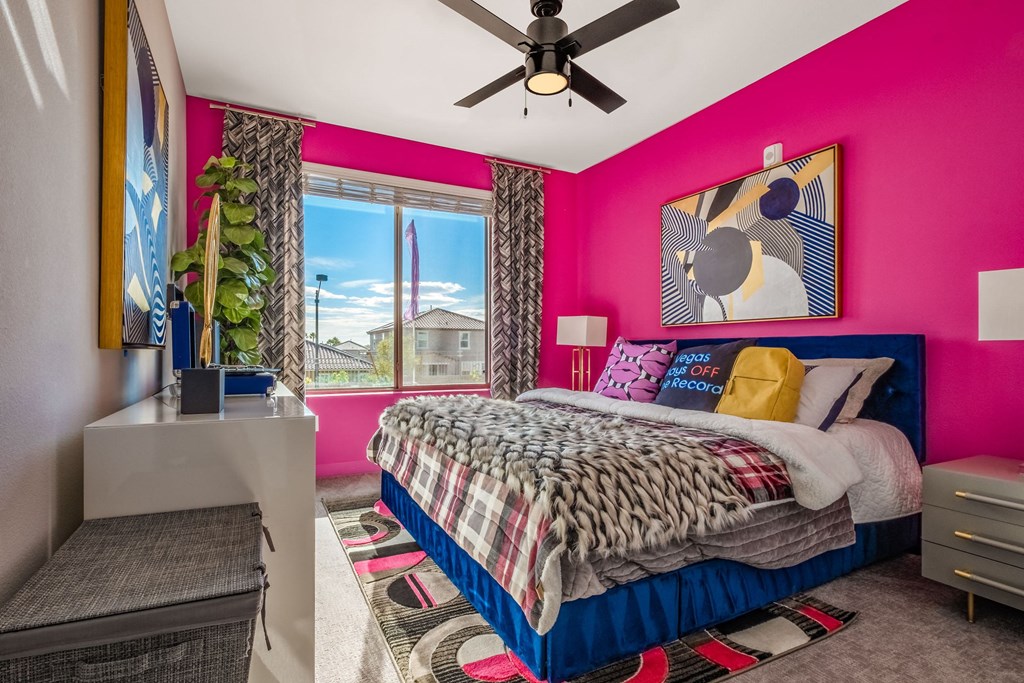 a bedroom with a bed and a pink wall and a ceiling fan