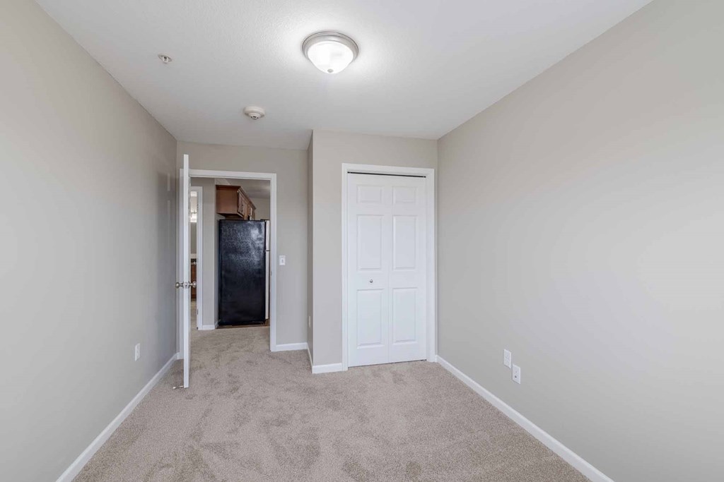 A room with a white door and a carpeted floor.