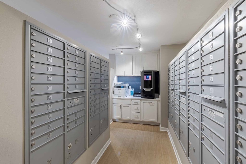 A room with a long row of mailboxes on both sides and a microwave in the middle.