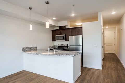 A kitchen with a granite countertop and stainless steel appliances at Emerald Crest, Bothell, Washington 98011