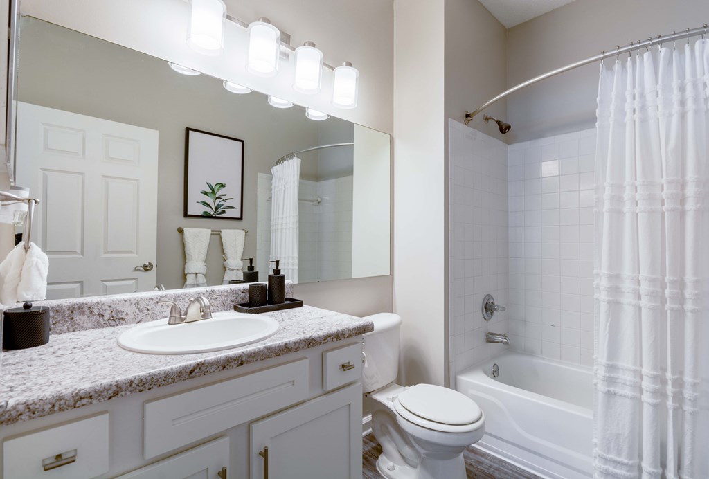 Renovated bathroom with large vanity and modern lighting at Enclave at Wolfchase Apartments in Cordova, TN.