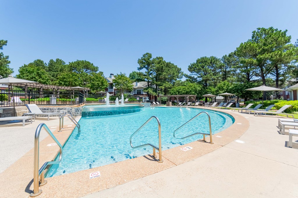 Sparkling outdoor swimming pool with sundeck at Enclave at Wolfchase Apartments in Cordova, TN.ladder and steps leading into the water.