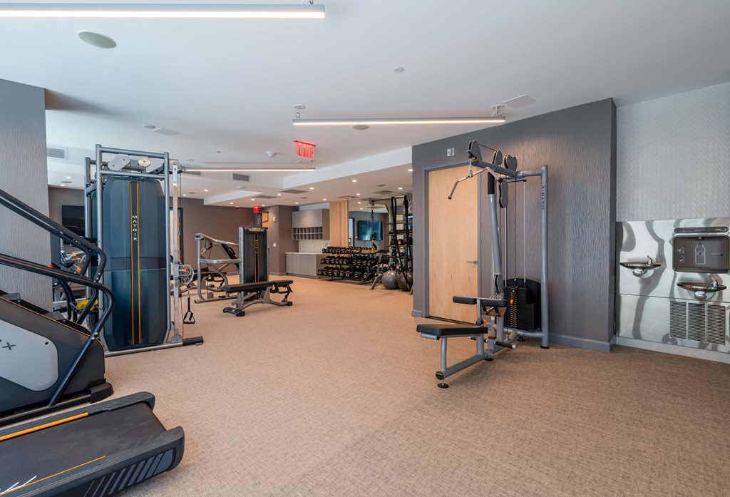 a gym with weights and cardio equipment on the floor and a mirrored wall