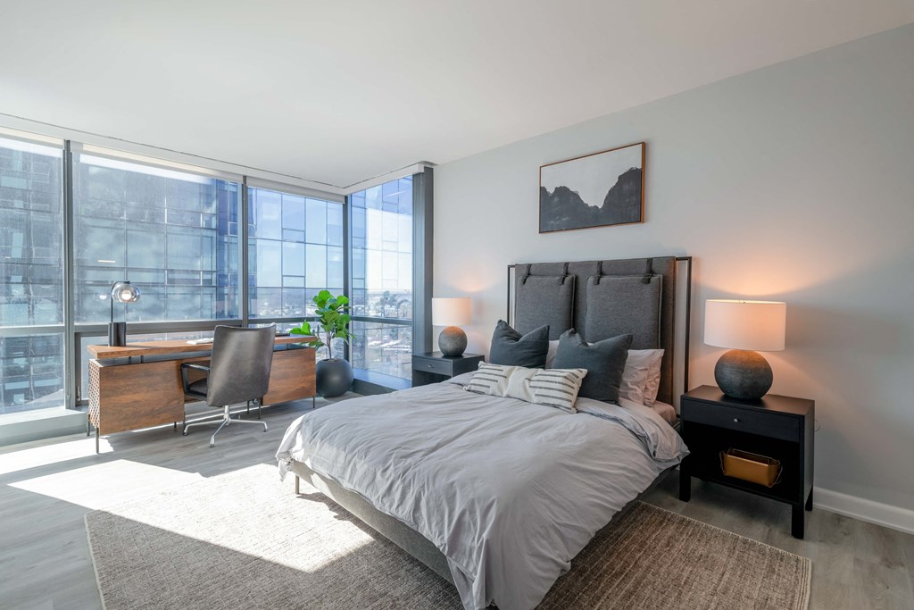 a bedroom with a bed and a desk with a large window