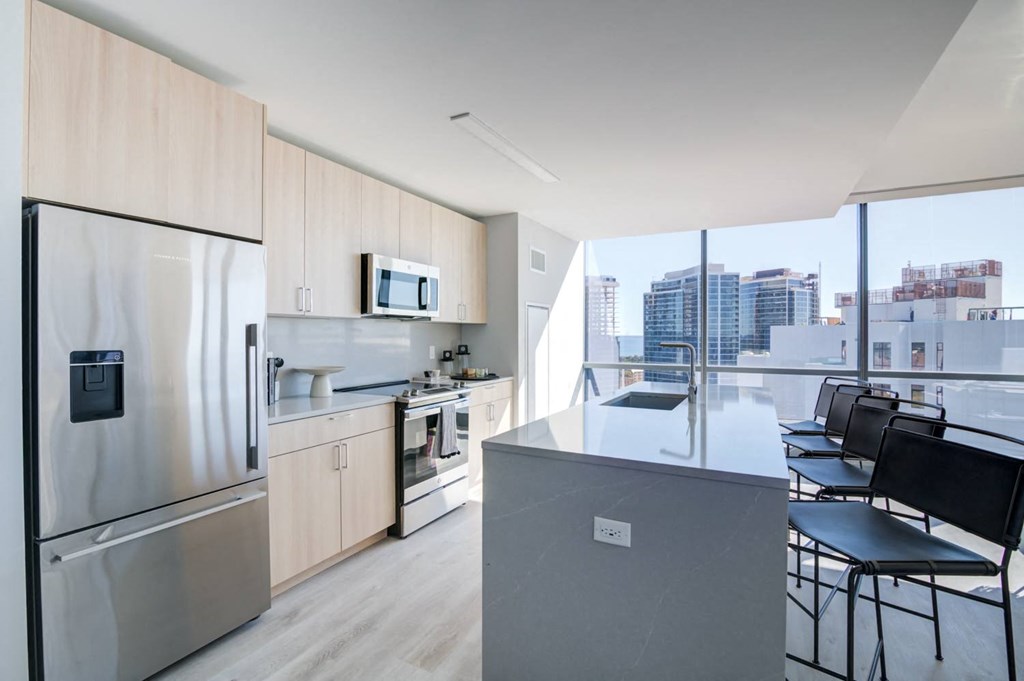 a kitchen with a large island and a stainless steel refrigerator
