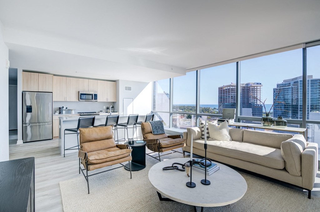 a living room with a view of a kitchen and a large window
