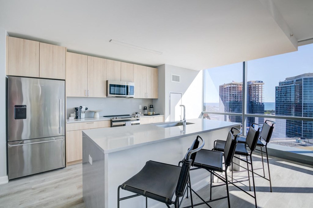 a kitchen with a counter and chairs in front of a window