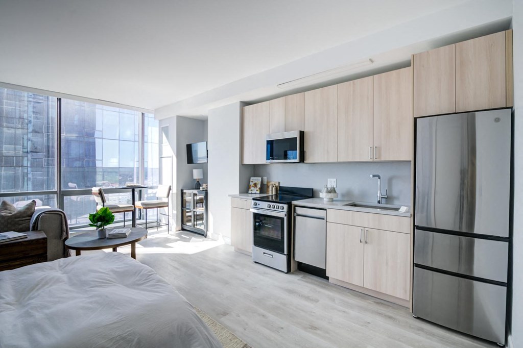 a bedroom with a bed and a kitchen with a refrigerator