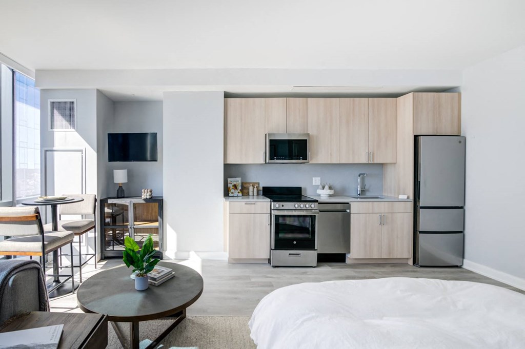 a bedroom with a bed and a kitchen with a refrigerator