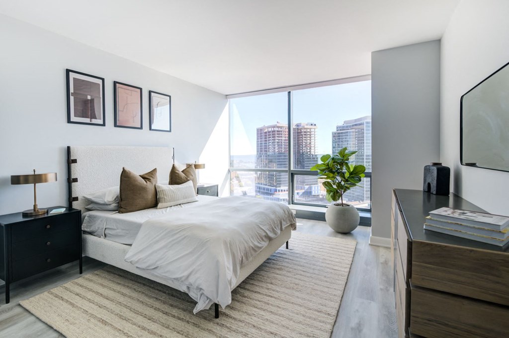 a bedroom with a large window and a bed and a rug
