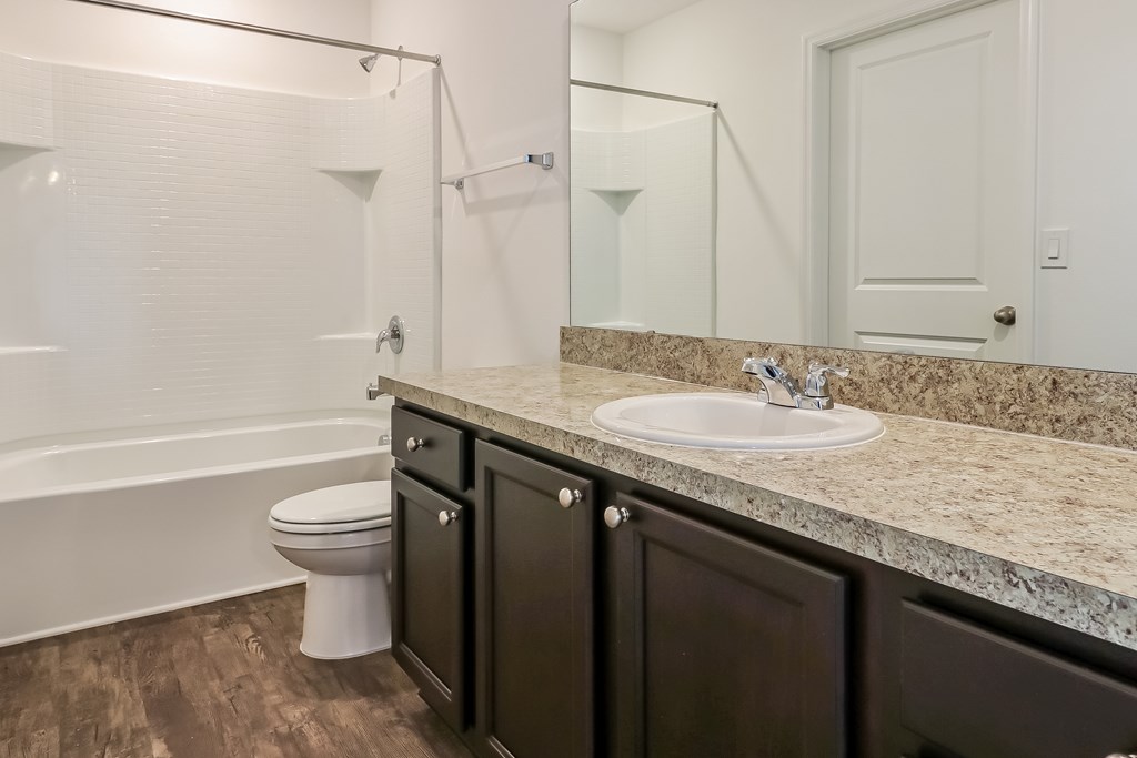 A white toilet sits in a bathroom with a marble countertop.