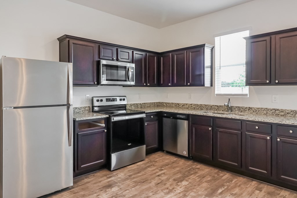 A kitchen with dark brown cabinets and a stainless steel refrigerator.