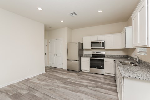 A kitchen with white cabinets and a grey floor.