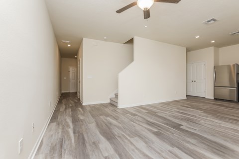 A room with a ceiling fan and a refrigerator.