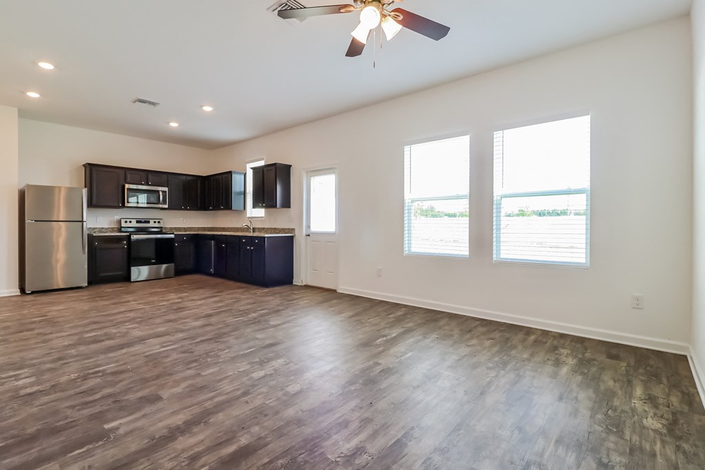 A spacious kitchen with dark wood floors and stainless steel appliances.