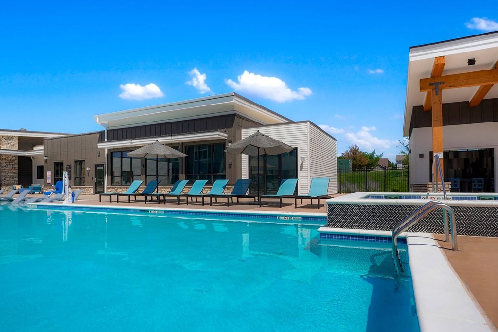 a swimming pool in front of a building with blue chairs