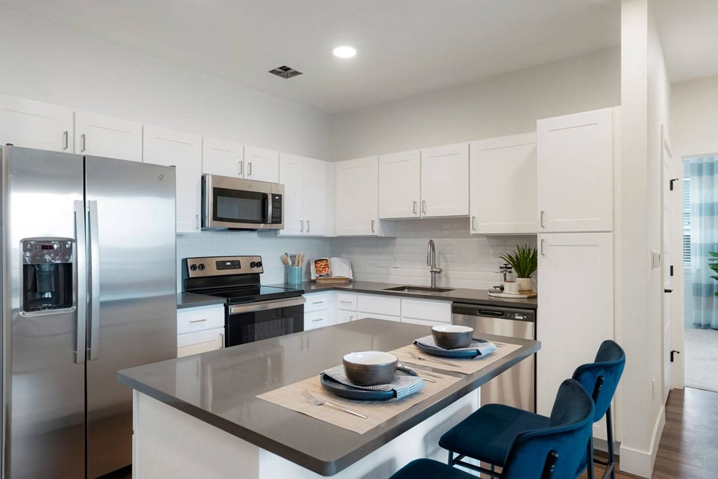 a kitchen with stainless steel appliances and an island with blue chairs