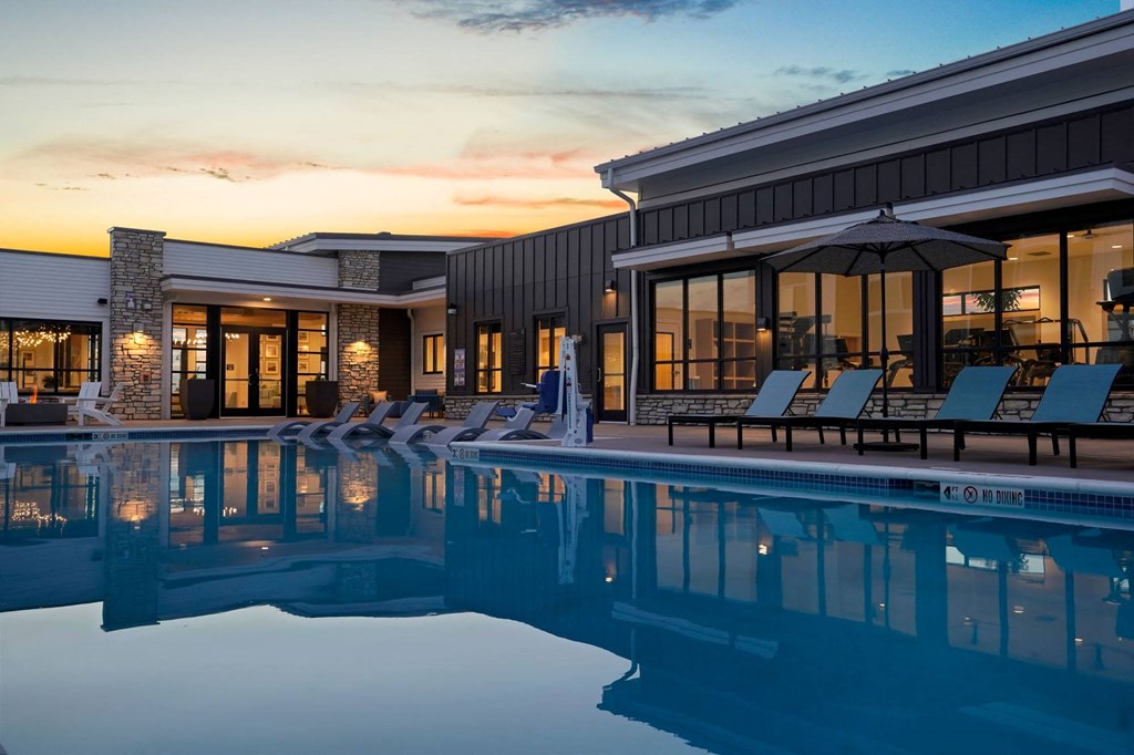 a pool with chairs and umbrellas next to a building