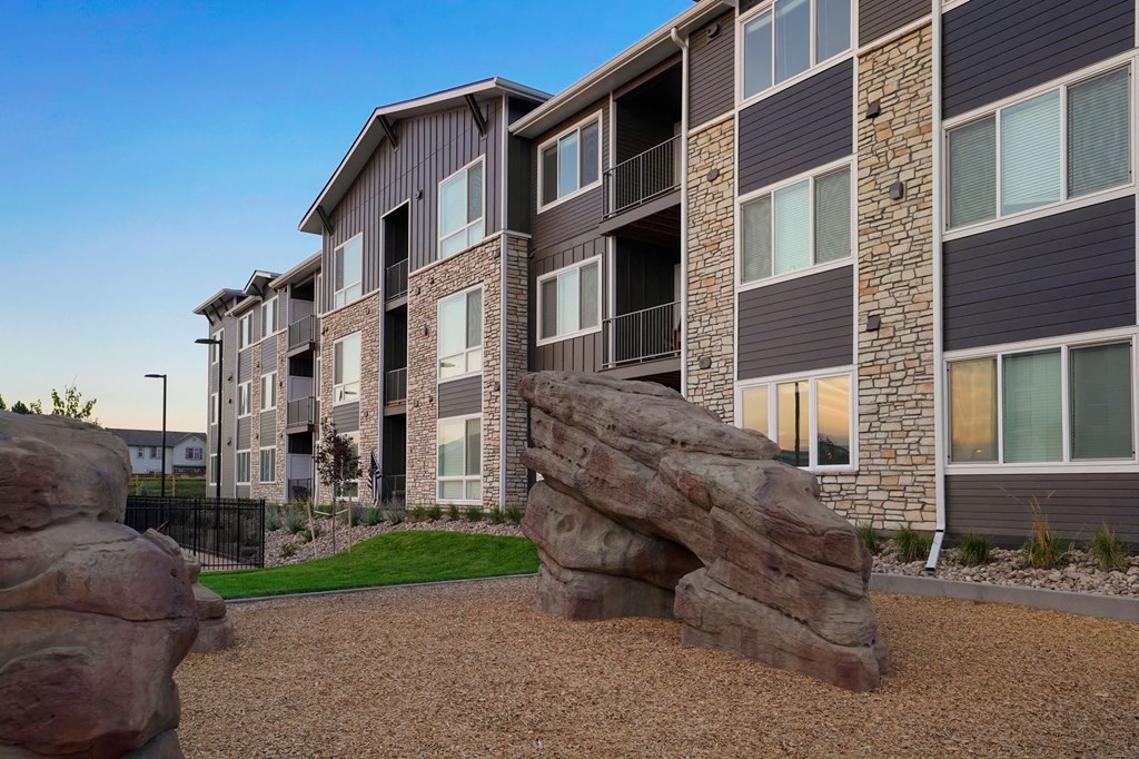 a building with a rock sculpture in front of it