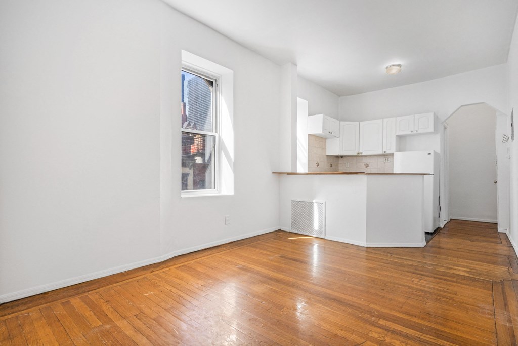 an empty living room with wood floors and a window