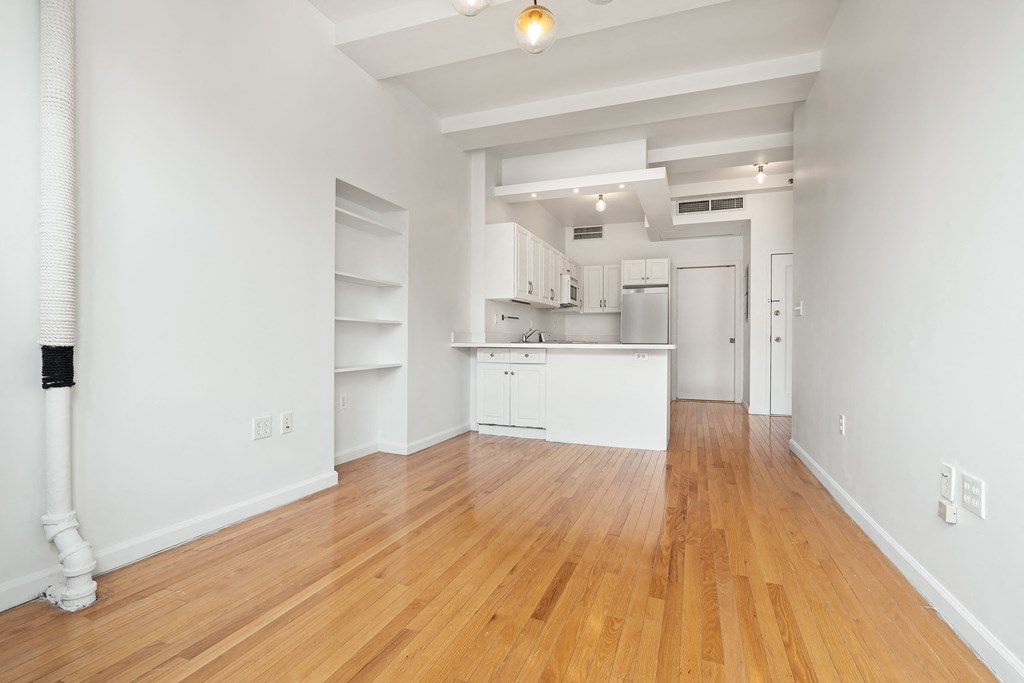 a living room and kitchen with wood floors and white walls