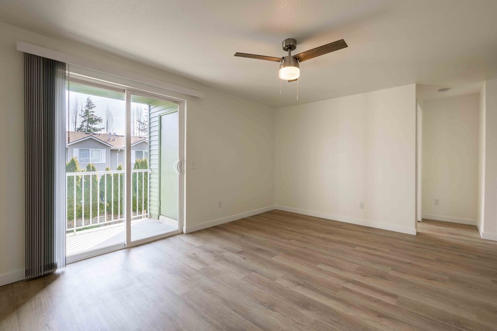an empty living room with a sliding glass door and a ceiling fan