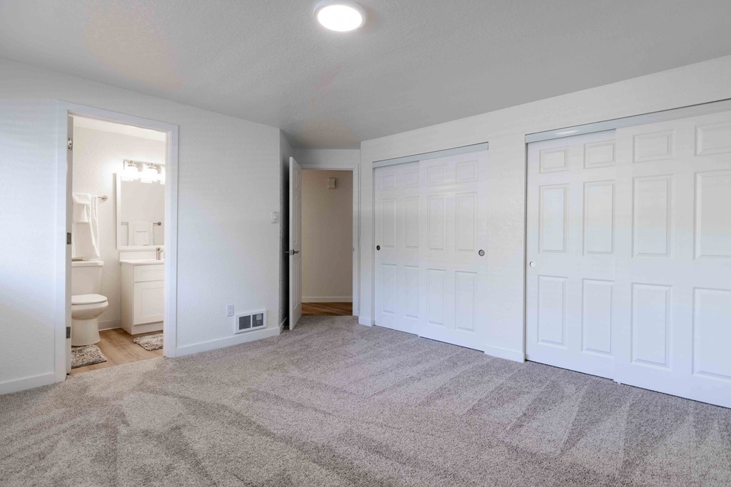 a bedroom with two closets and a bathroom in the background