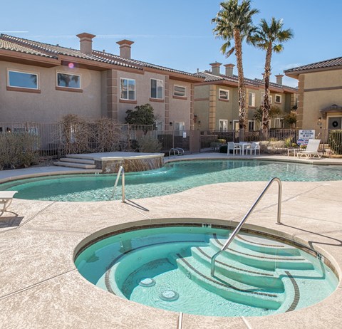 a swimming pool with a hot tub in front of an apartment building