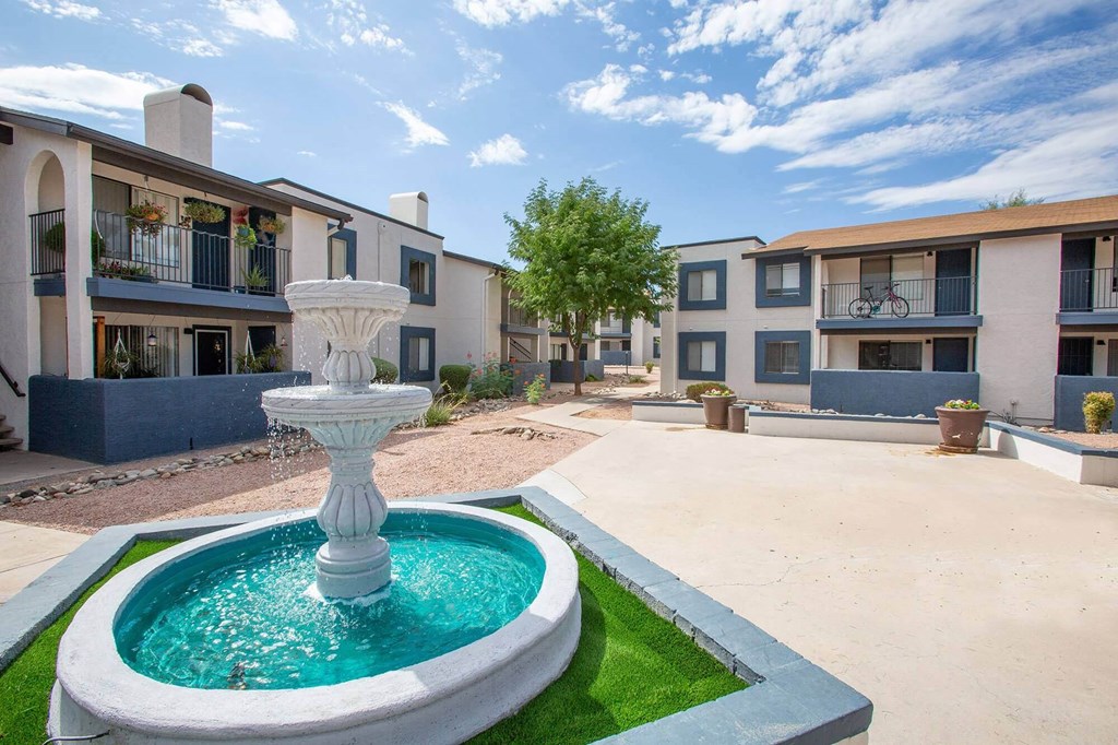 a fountain in the middle of a courtyard with apartments in the background