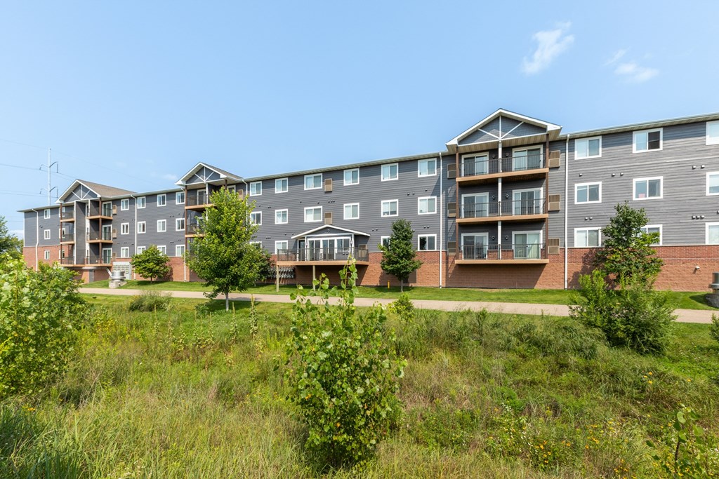 A large apartment complex with multiple balconies and greenery in the foreground.