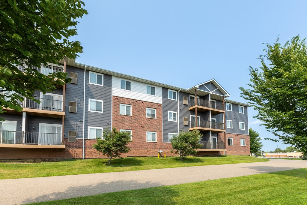 A large apartment building with multiple balconies and a driveway in front.