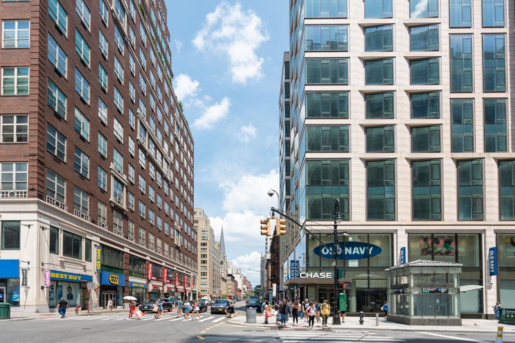 people crossing a busy city street in front of tall buildings