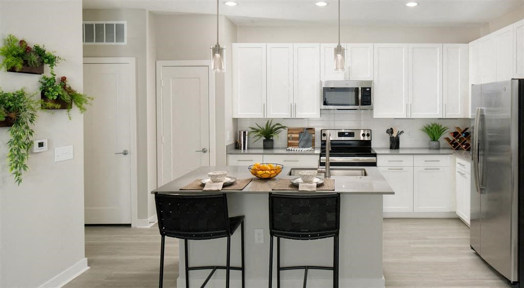 Modern kitchen with white cabinets, stainless steel appliances, and island with seating.