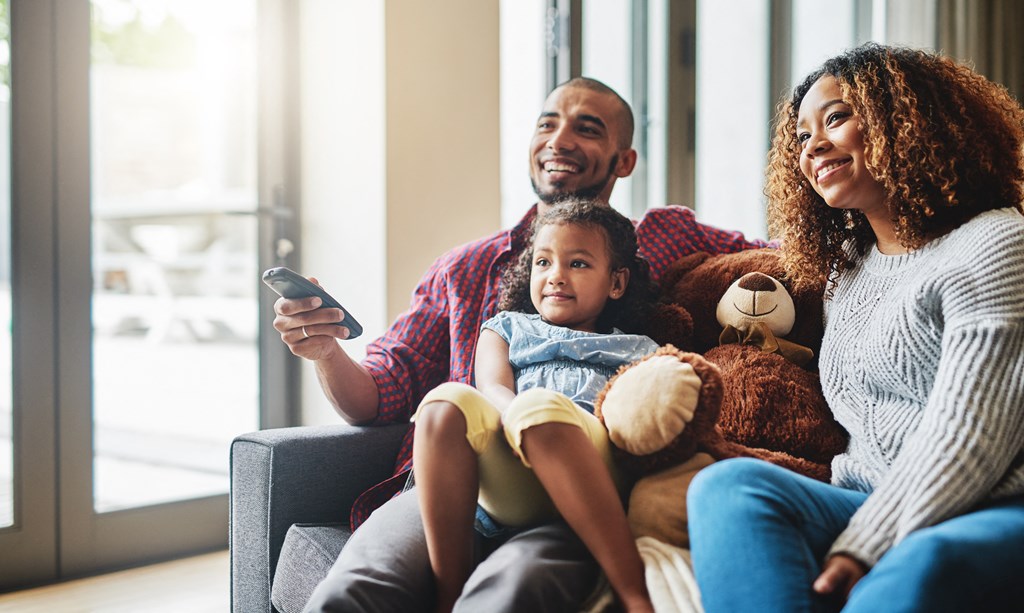 a man and woman sitting on a couch with a child and a teddy bear