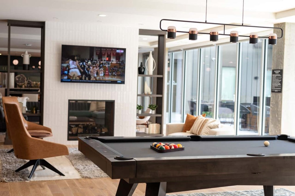 A pool table with a television in the background.