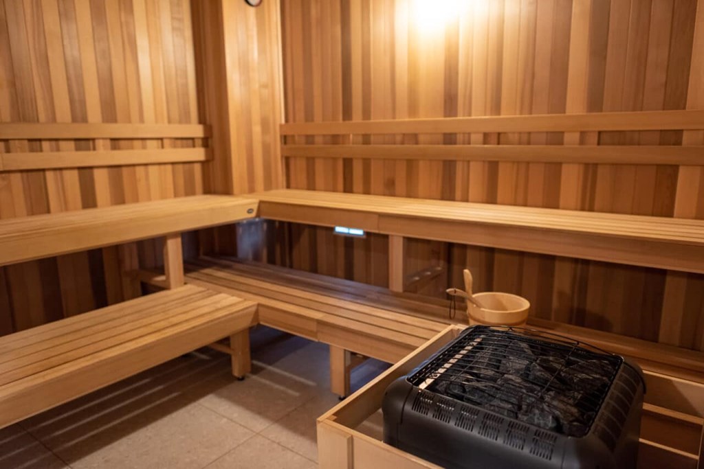 A sauna room with wooden benches and a bench with a black cover on it.