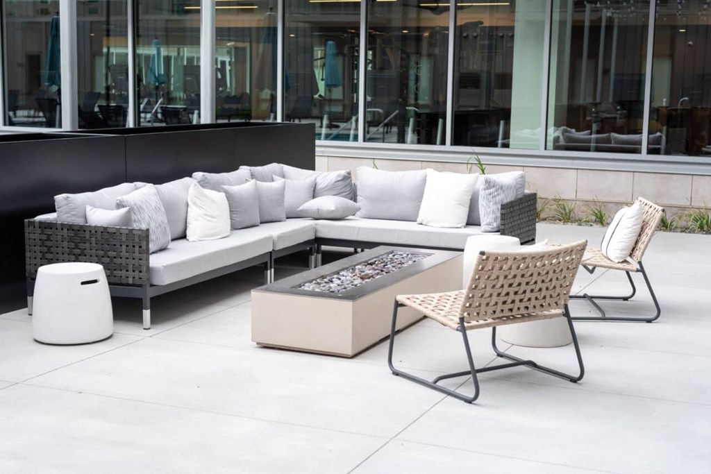 A patio furniture set with a white couch, pillows, and a fire pit.