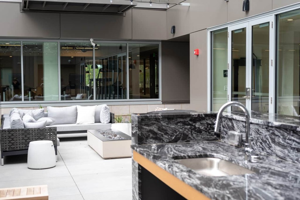 A modern kitchen with a marble countertop and a large window.