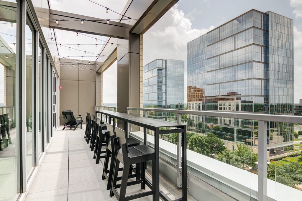A balcony with a table and chairs overlooking a cityscape.