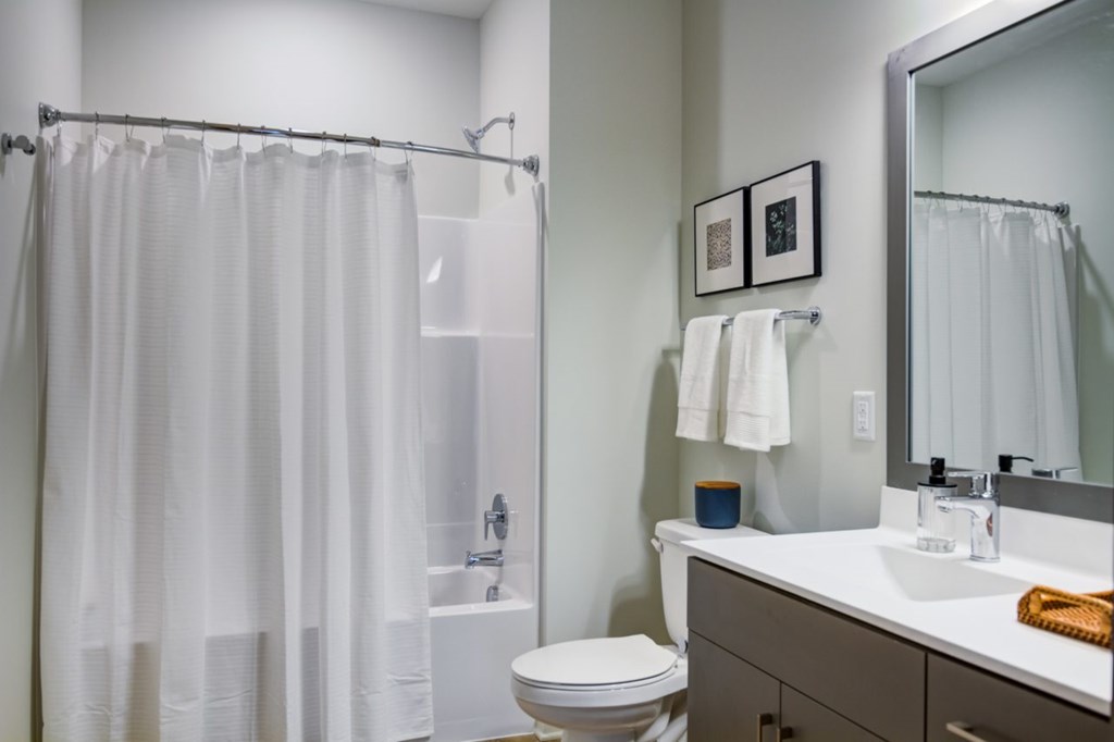 Luxury Apartments for rent in Bloomington, MN - The Fenley - Spacious Bathroom with a Vanity Sink with White Countertops, a Large Mirror, a Shower and Bathtub Combo