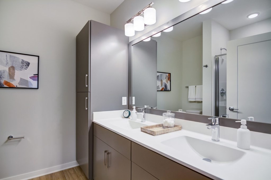 A bathroom with a white sink and a brown cabinet.