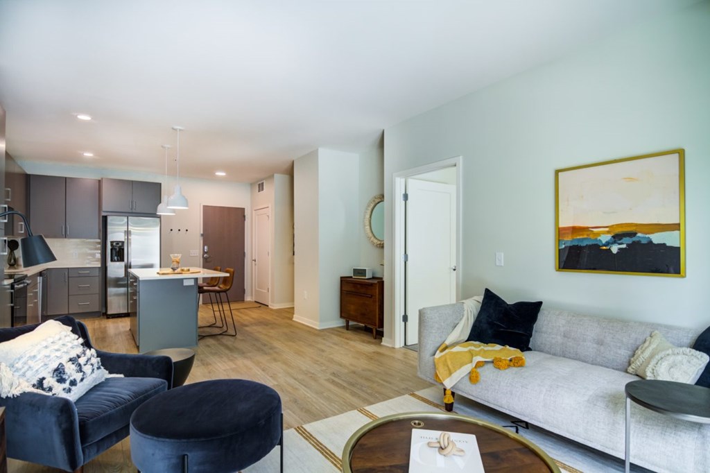 A living room with a grey couch, a black ottoman, and a coffee table.