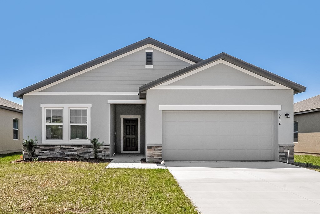 A modern house with a grey garage door and a black front door.