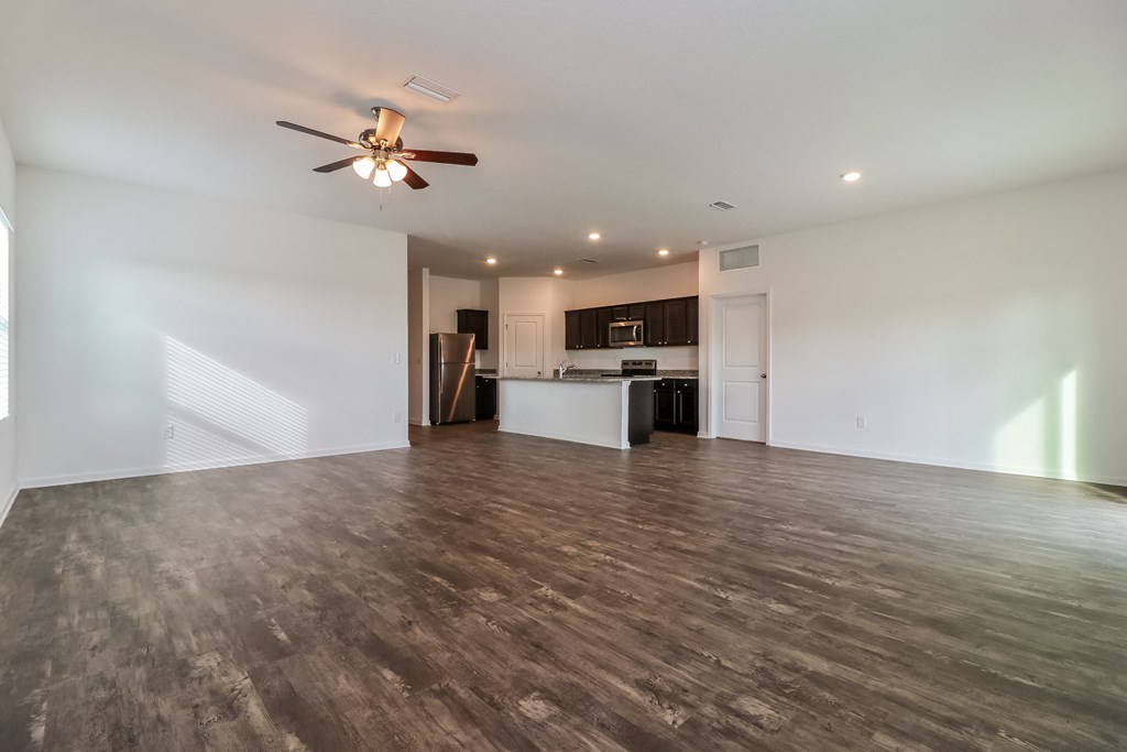 A spacious room with a ceiling fan and wooden flooring.