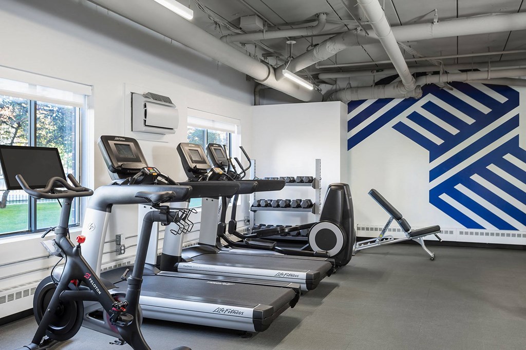 a gym with treadmills and other exercise equipment in a room with a window