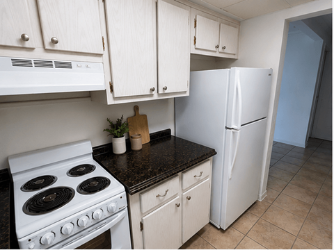A kitchen with a white stove and a white refrigerator.